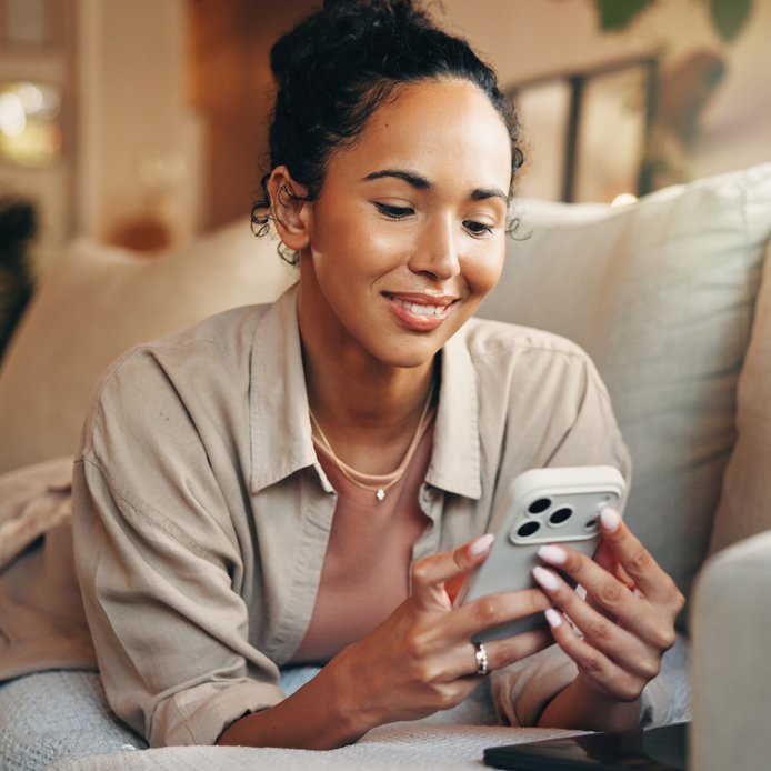 Étudiante souriante avec son ordinateur portable, installée dans son logement